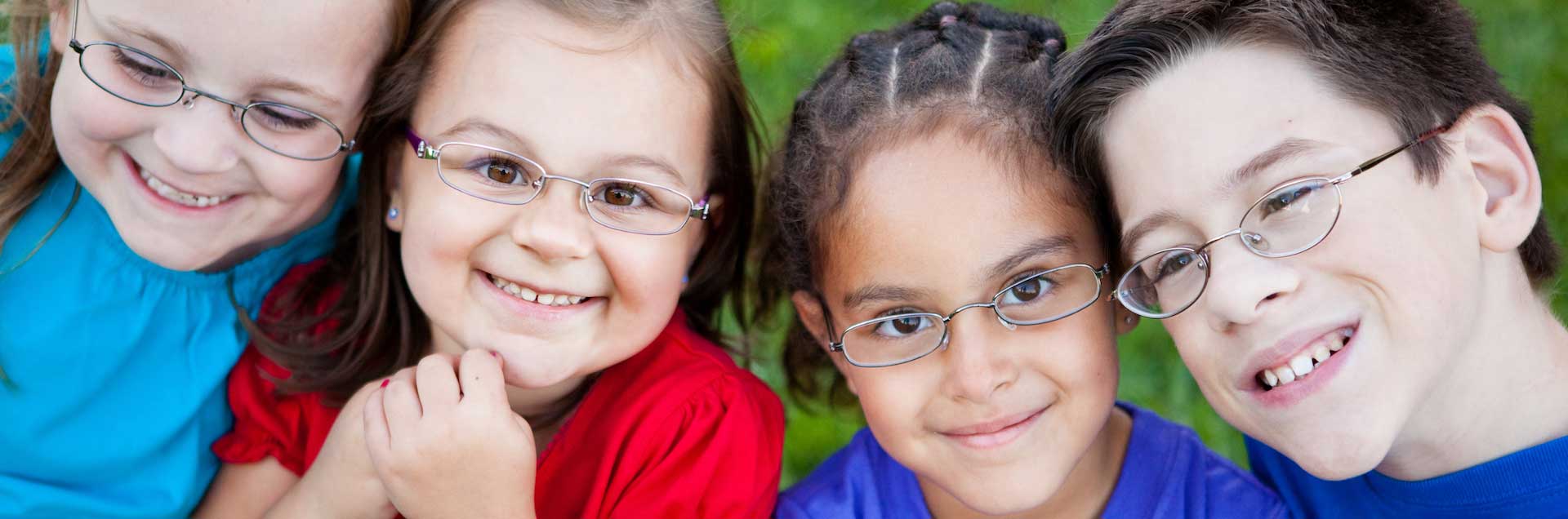 Smiling children wearing eyeglasses outdoors.